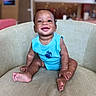 baby, child, smiling, blue_onesie, armchair, sitting, happy, indoors, portrait, cute, infant, skin, face, feet, hands, furniture, background_blur, expression, young, person