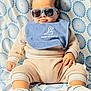 Censio joined the competition — help win amazing prizes! baby, child, sunglasses, bib, cute, sitting, clothing, footwear, patterned_background, blue, beige, portrait, indoor, infant, hand, face, head, smile, fashion, casual