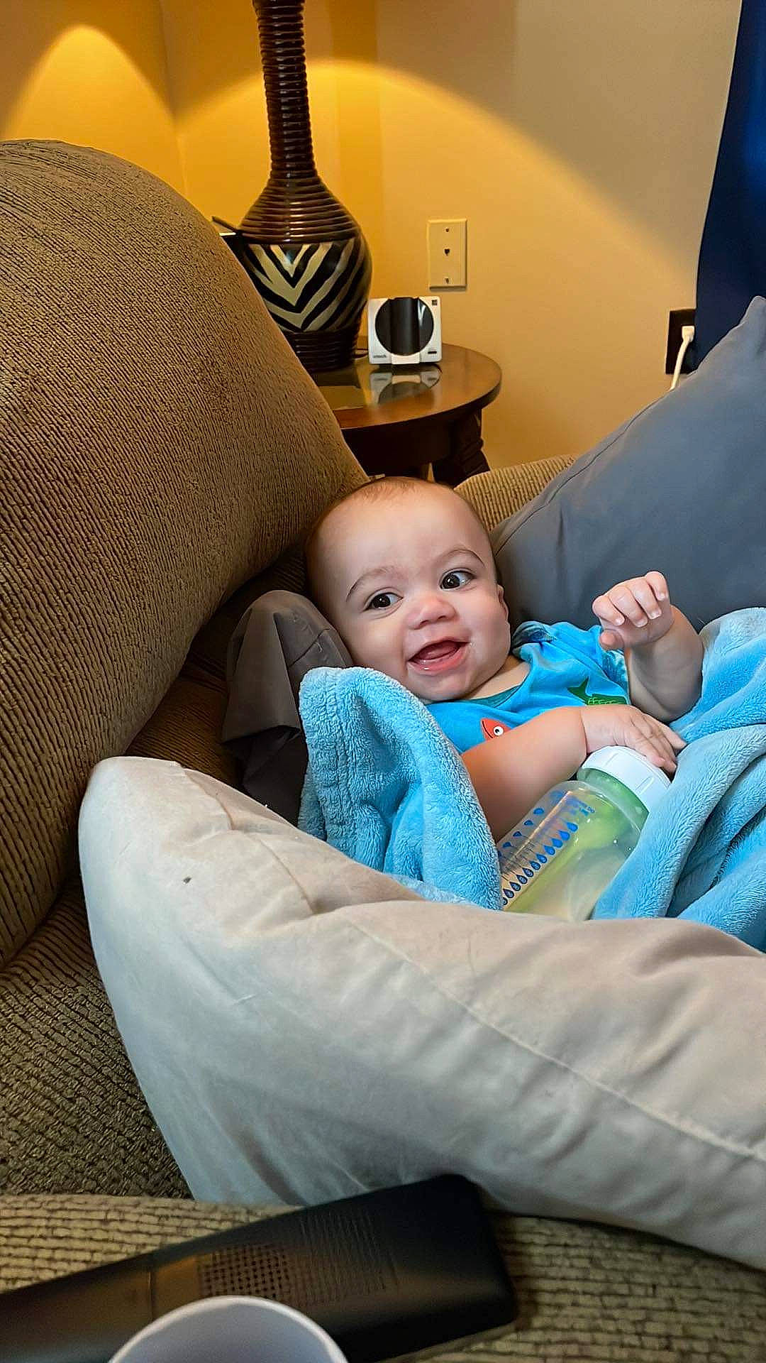 Johnathan is registered to the contest to win money with this photo: baby, baby_toddler_clothing, blue, chair, child, comfort, couch, event, fun, happy, lamp, lap, leisure, living_room, luxury_vehicle, person, picture_frame, room, sitting, smile