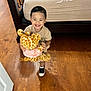Aron joined the competition — help win amazing prizes! child, toddler, smiling, stuffed_animal, giraffe, toy, bed, wooden_floor, indoor, happy, person, clothing, footwear, shorts, shirt, black_shoes, white_socks, hair, holding, playful