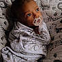 baby, pacifier, blanket, wrap, cushion, animal_print, infant, cozy, sleeping_area, child, portrait, indoors, soft_lighting, cute, resting, wrapped, young, peaceful, face, baby_girl