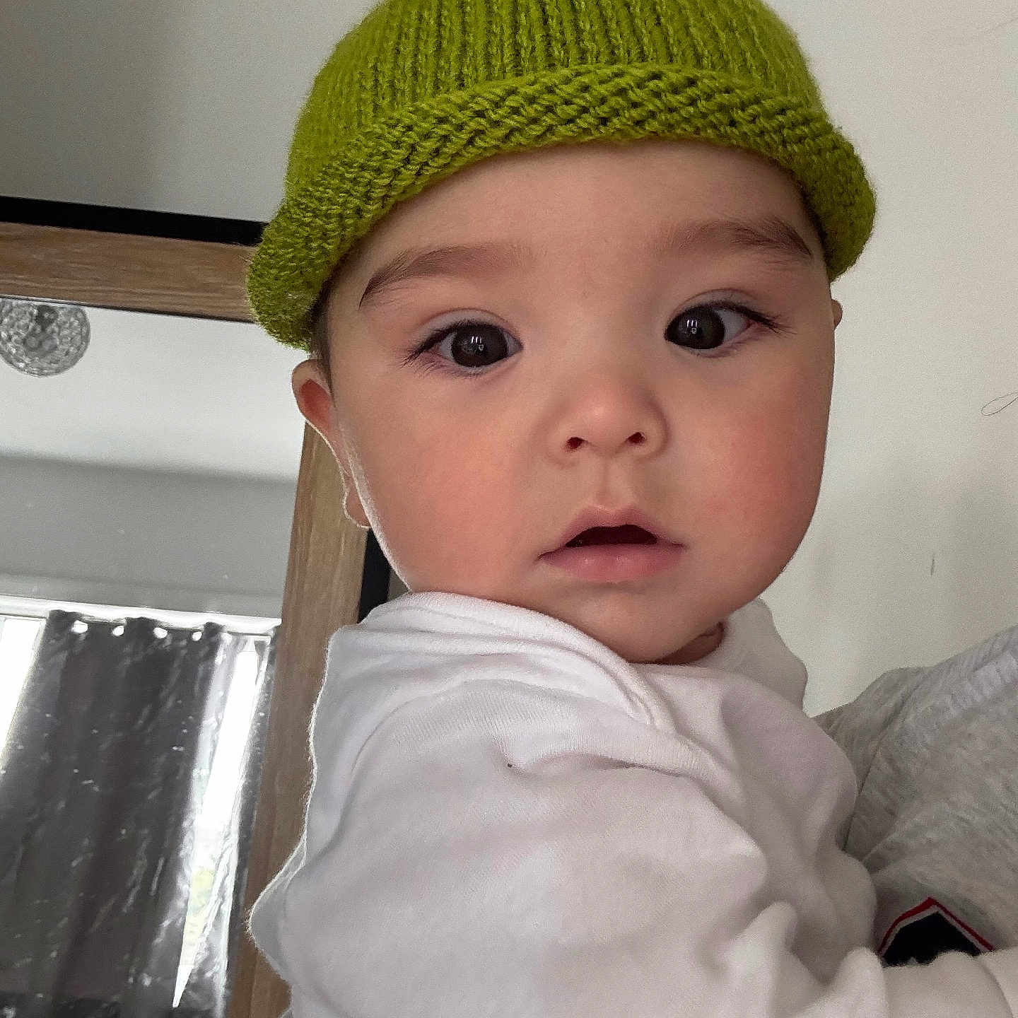Salim joined the competition — help win amazing prizes! baby, child, closeup, curtain, cute, expression, eyelashes, face, hat, headwear, indoor, knit_hat, looking, mirror, person, portrait, skin, sleeve, white_clothing, young_child