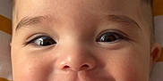 Salim joined the competition — help win amazing prizes! baby, close_up, face, finger, smile, cute, infant, skin, eyebrows, cheeks, mouth, eyes, expression, hand, lying_down, blanket, pattern, white_clothing, soft_light, portrait