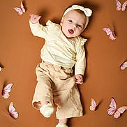 Anna participe au concours pour gagner de l'argent avec cette photo : baby, infant, headband, butterfly, adorable, smile, lying_down, studio_shot, portrait, soft_lighting, beige_background, yellow_clothing, socks, cute, one_person, wide_eyes, playful, decorative_butterflies, pale_pants, small_hands