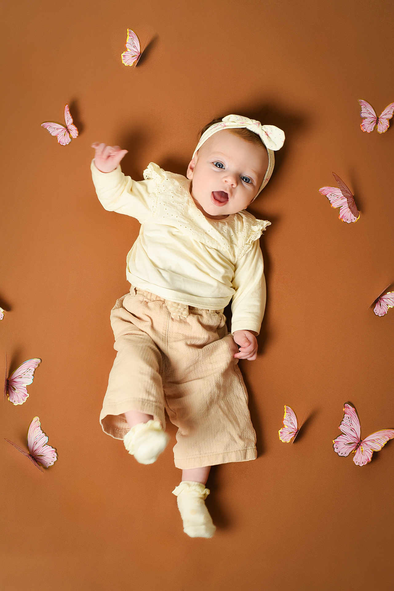 Anna participe au concours pour gagner de l'argent avec cette photo : baby, infant, headband, butterfly, adorable, smile, lying_down, studio_shot, portrait, soft_lighting, beige_background, yellow_clothing, socks, cute, one_person, wide_eyes, playful, decorative_butterflies, pale_pants, small_hands