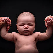 Elijah is registered to the contest to win money with this photo: baby, infant, hands, holding, tattoo, peaceful, sleeping, skin, closeup, portrait, newborn, human, parental, connection, black_background, soft_light, cute, child, love, tenderness