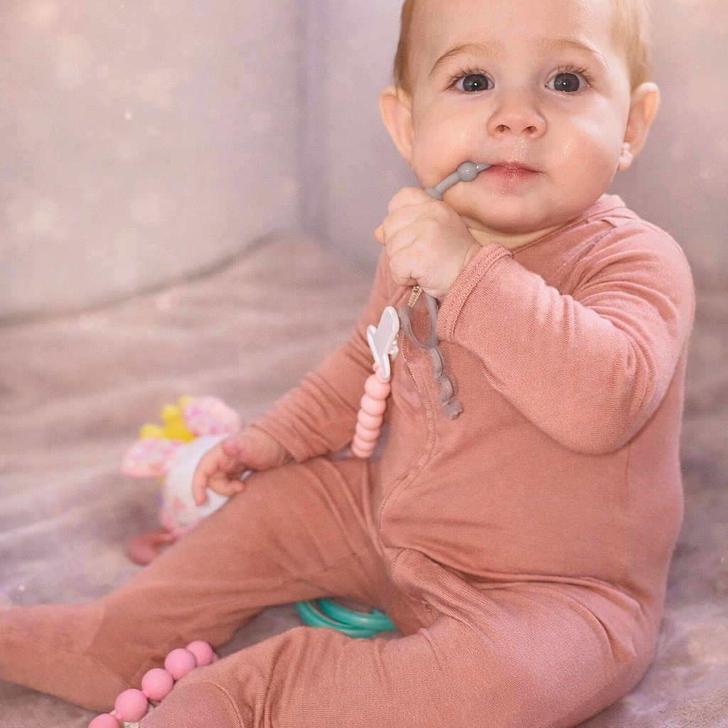 Estrada is registered to the contest to win money with this photo: baby, child, comfort, cute, expression, face, hand, home, indoor, infant, onesie, pink, playtime, portrait, sitting, soft_blanket, teether, toy, warm_light, young_child