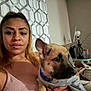 Max is registered to the contest to win money with this photo: woman, dog, indoor, holding, curtain, patterned_curtain, casual_clothing, light_bulb, table, container, lamp, earrings, face, pet, furniture, portrait, couch, hair, collar, sitting