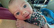 Adeline is registered to the contest to win money with this photo: baby, infant, face, hand, car_interior, floral_clothing, person, closeup, eyes, skin, car_seat, blue_bag, dashboard, seatbelt, human, cute, portrait, newborn, child, car