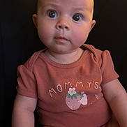 Adeline is registered to the contest to win money with this photo: arm, baby, child, clothing, curious, cute, expression, eyes, face, furniture, head, indoor, infant, leg, onesie, person, portrait, sitting, skin, strawberry