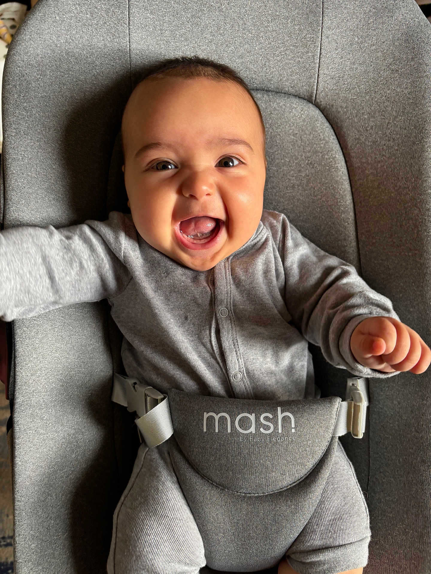 Rafael is registered to the contest to win money with this photo: baby, infant, smile, happy, grey_clothing, baby_seat, straps, face, mouth_open, arms_outstretched, indoor, child, cute, joyful, person, one_person, young_child, seat, fabric, closeup