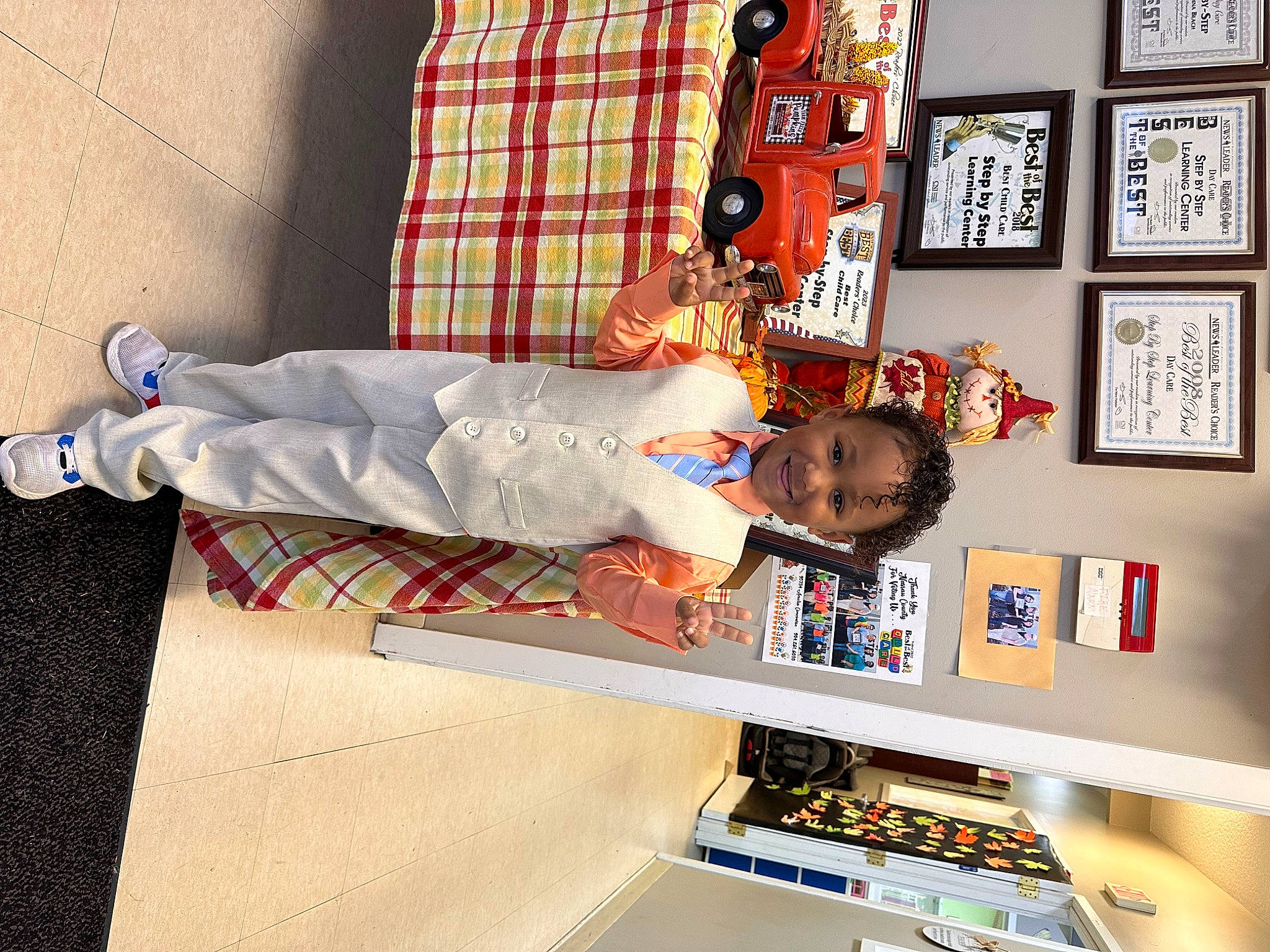 Kyree joined the competition — help win amazing prizes! art, child, collection, flooring, joy, linens, orange, pattern, person, picture_frame, plaid, red, room, shelf, shelving, sleeve, smile, t_shirt, tartan, textile