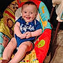 Remington is registered to the contest to win money with this photo: baby, child, smile, happy, infant, onesie, blue_clothing, baby_seat, animal_prints, giraffe, lion, elephant, floor, wooden_floor, indoor, cute, chubby_legs, bright_colors, playful, portrait