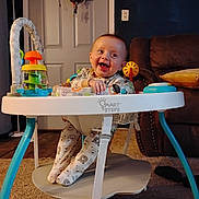 Remington is registered to the contest to win money with this photo: baby, walker, pajamas, smiling, toy, indoor, carpet, couch, door, lamp, living_room, child, happy, footwear, seat, furniture, person, playtime, infant, clothing