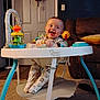 baby, walker, pajamas, smiling, toy, indoor, carpet, couch, door, lamp, living_room, child, happy, footwear, seat, furniture, person, playtime, infant, clothing