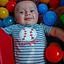 Remington joined the competition — help win amazing prizes! baby, child, smiling, striped_onesie, baseball_design, ball_pit, red_ball, yellow_ball, blue_ball, translucent_ball, playful, happy, infant, cute, indoor, colorful, person, face, young_child, toy