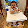 baby, high_chair, smiling, indoor, floor_tiles, plant, window, curtains, pacifier, slippers, baby_bear, child, person, happy, footrest, wooden, striped_shirt, home, furniture, cute