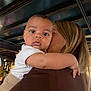 baby, child, person, indoor, holding, adult, face, curious, closeup, portrait, warm_lighting, wooden_beams, clothing, expression, candid, family, love, toddler, skin, arm