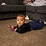 Xain joined the competition — help win amazing prizes! baby, child, toddler, infant, lying_down, tummy_time, rattle, toy, indoor, living_room, couch, blankets, carpet, portrait, looking_at_camera, wide_eyes, black_shirt, blue_pants, socks, home