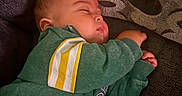 Xain is registered to the contest to win money with this photo: baby, infant, sleeping, couch, sofa, pillow, indoors, portrait, green_clothing, striped_sleeves, resting, peaceful, face, closed_eyes, hands, fabric, home, soft_lighting, cozy, nap