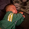 baby, infant, sleeping, couch, sofa, pillow, indoors, portrait, green_clothing, striped_sleeves, resting, peaceful, face, closed_eyes, hands, fabric, home, soft_lighting, cozy, nap