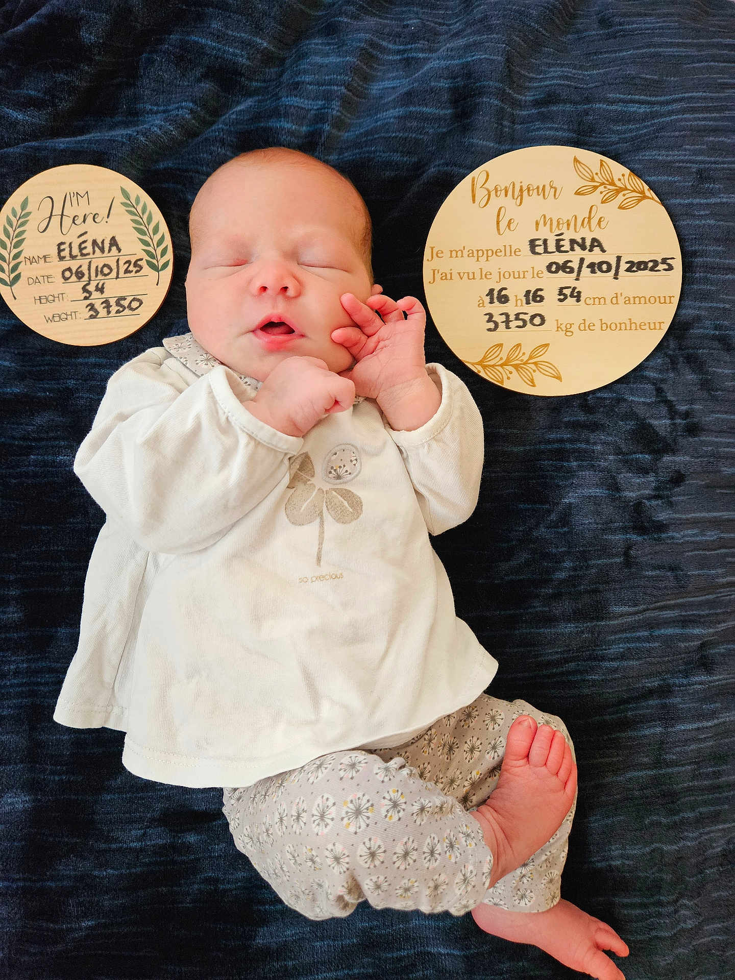 Eléna a rejoint le concours — aidez-le/la à gagner de superbes lots ! newborn, baby, infant, sleeping, clothing, blanket, plaque, wood, text, face, hand, foot, patterned_pants, white_shirt, portrait, laying_down, cute, peaceful, indoors, baby_photo