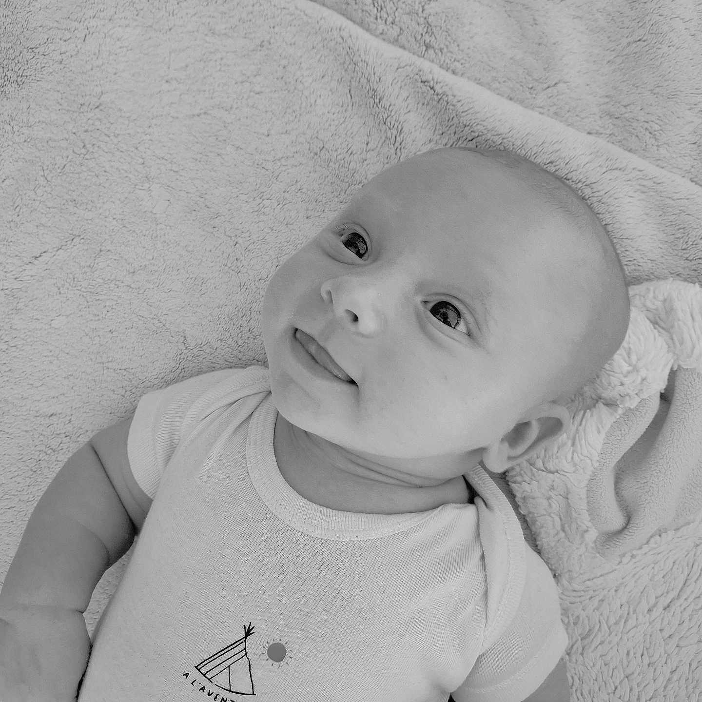 Nino a rejoint le concours — aidez-le/la à gagner de superbes lots ! baby, black_and_white, blanket, child, cute, expression, face, hand, head, infant, looking_up, lying_down, monochrome, onesie, portrait, sleepwear, smiling, soft_texture, tongue_out, young
