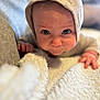 baby, child, face, blue_eyes, knitted_hat, blanket, closeup, portrait, infant, curious, soft_texture, couch, indoors, cozy, cute, young_child, hand, skin, expression, warm_lighting