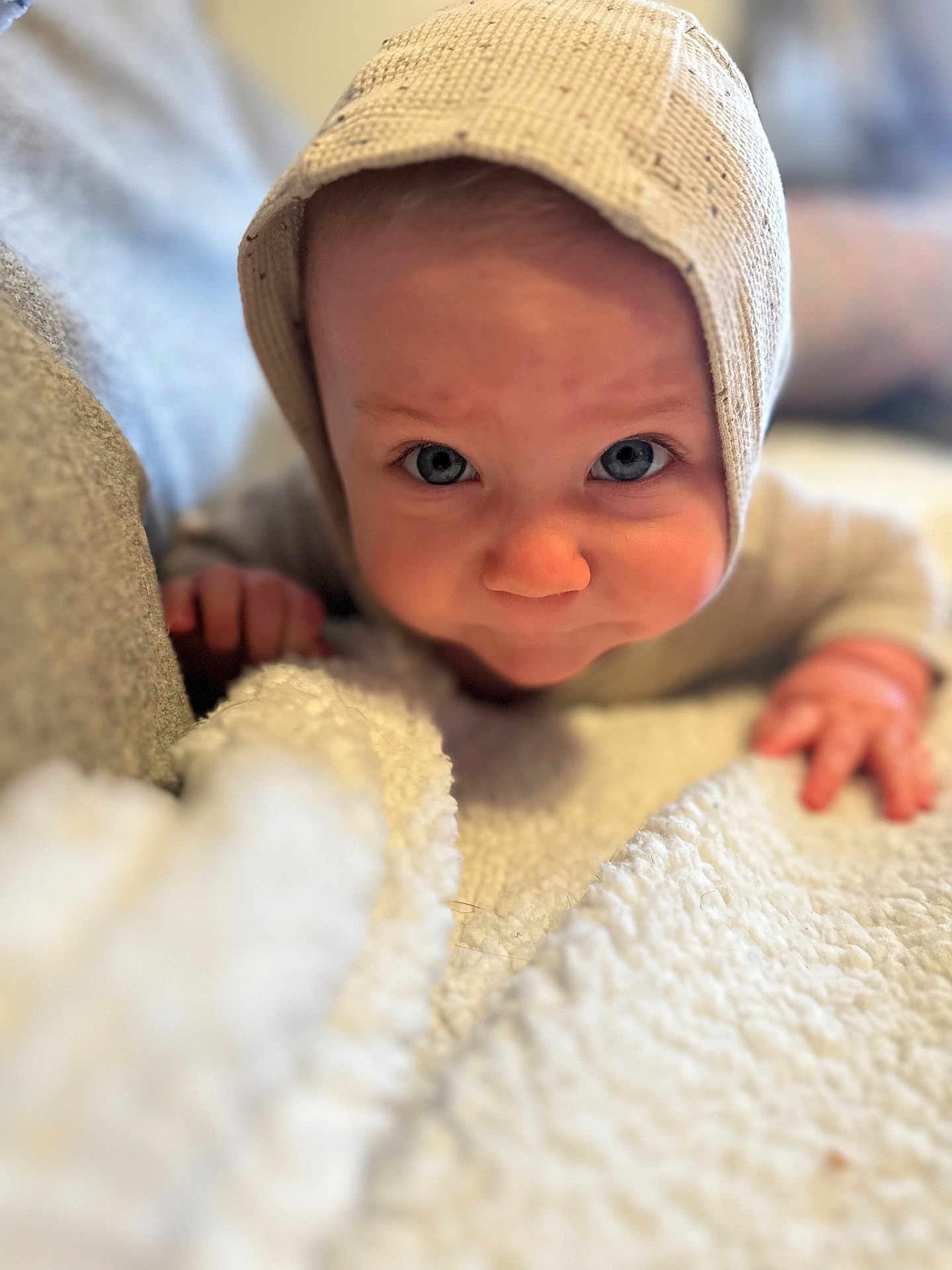 Oliver joined the competition — help win amazing prizes! baby, child, face, blue_eyes, knitted_hat, blanket, closeup, portrait, infant, curious, soft_texture, couch, indoors, cozy, cute, young_child, hand, skin, expression, warm_lighting