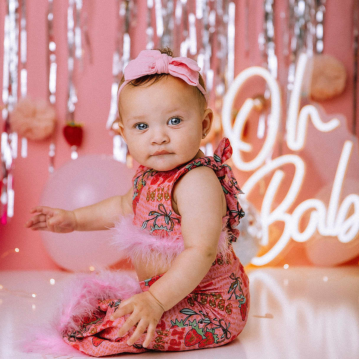 Damzynn is registered to the contest to win money with this photo: baby, background, balloon, blue_eyes, bow, celebration, child, cute, decorations, dress, expression, face, feathers, headband, indoor, party, pink, portrait, sitting, strawberry