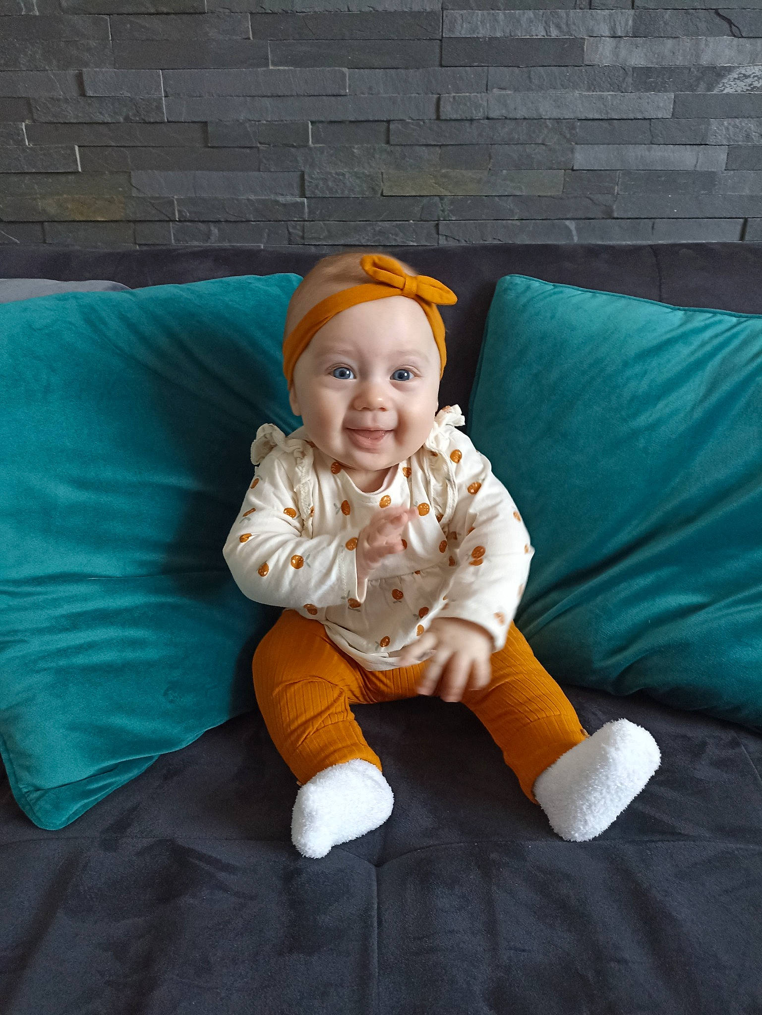 Emma participe au concours pour gagner de l'argent avec cette photo : baby, baby_toddler_clothing, brick, comfort, couch, eye, flooring, foot, fun, happy, hat, head, human_body, lap, linens, person, portrait_photography, sitting, sleeve, smile