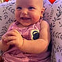 baby, smiling, pink_outfit, cushion, patterned, heart_emoji, indoor, happy, child, cute, portrait, infant, sitting, hands, cheeks, closeup, bright_eyes, soft_lighting, comfortable, adorable