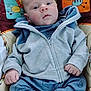 animal_print, baby, child, clothing, colorful, cozy, cushion, cute, expression, face, feet, hands, indoor, infant, jacket, looking, pants, portrait, sitting, young