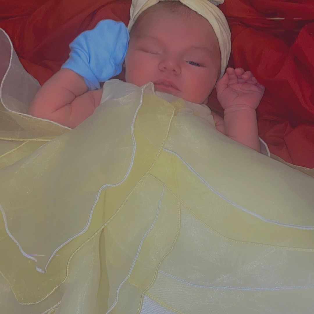 Esther joined the competition — help win amazing prizes! baby, blanket, blue_mitten, child, clothing, colorful, cute, dress, headband, indoors, infant, lying_down, mitten, newborn, portrait, red_blanket, resting, sleeping, soft_fabric, yellow_dress