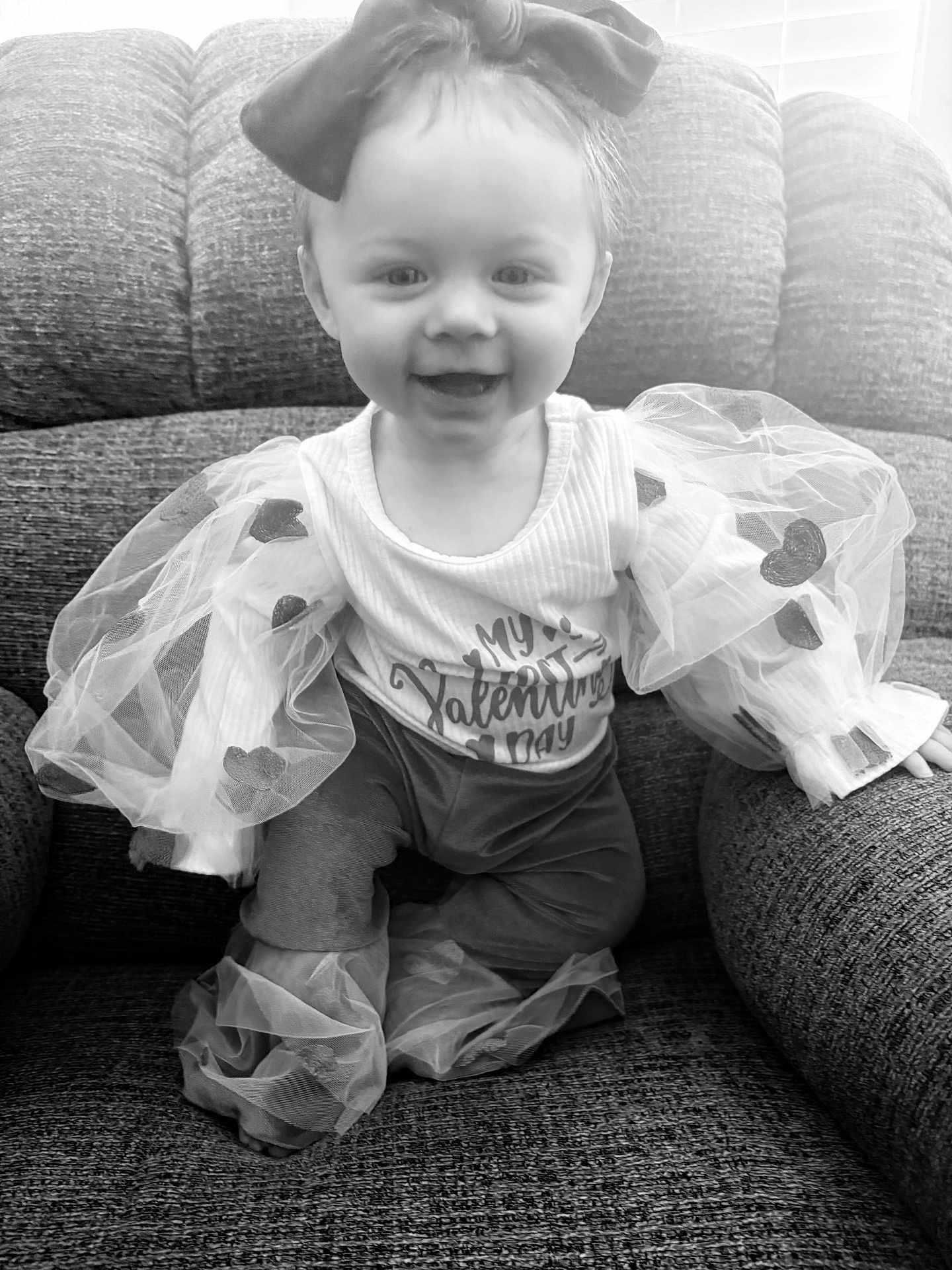 Octavia is registered to the contest to win money with this photo: baby, child, smiling, couch, clothing, portrait, tulle, puffy_sleeves, ribbons, happy, indoor, seated, face, headband, cute, monochrome, fabric, texture, person, young