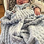 baby, blanket, blue, cushion, face, hand, infant, indoors, light, person, playful, seat, soft, smile, toy, wood_floor, young_child, cozy, comfort, happy