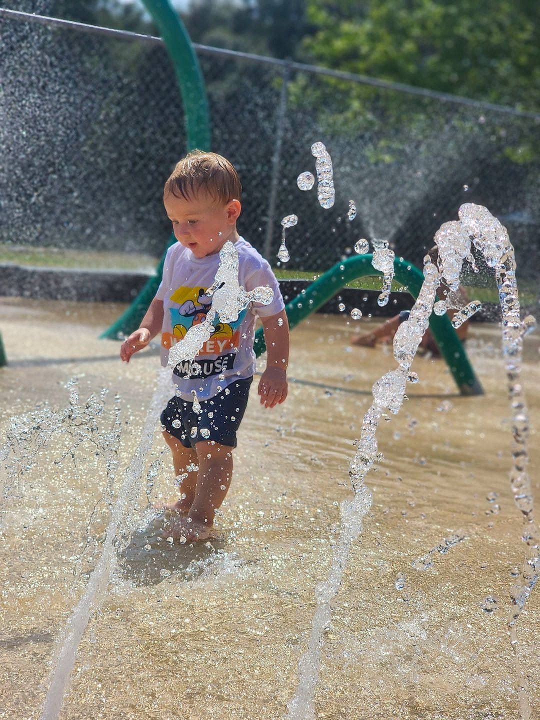 Layne is registered to the contest to win money with this photo: barefoot, child, city, event, fountain, fun, grass, happy, leisure, person, play, recreation, sand, shorts, smile, soil, toddler, vacation, water, water_feature