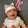 baby, infant, smiling, hat, bear_ears, polka_dot, shirt, hand, pink_bow, headband, gray_background, happy, cute, child, lying_down, closeup, apparel, cheerful, playful, adorable