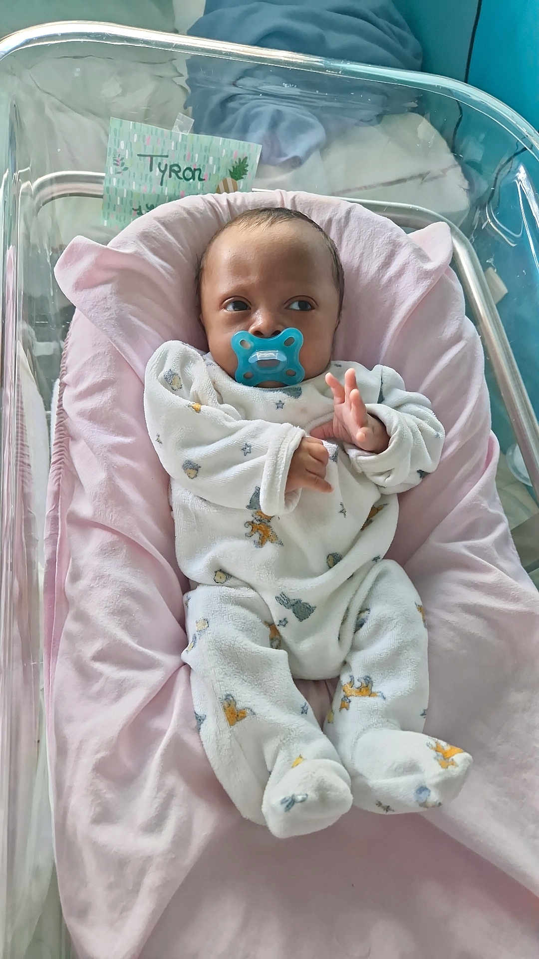 Tyron a rejoint le concours — aidez-le/la à gagner de superbes lots ! baby, infant, pacifier, crib, blanket, pink, white_clothing, onesie, face, newborn, sleeping_area, soft_toy_pattern, hospital_bassinet, hand, footed_pajamas, cute, child, person, indoor, resting