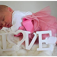 Iris participe au concours pour gagner de l'argent avec cette photo : baby, newborn, sleeping, pink_tutu, white_clothing, love_sign, blanket, soft_texture, cute, infant, peaceful, resting, indoors, portrait, closeup, tulle_skirt, decorative_letters, sleep, tiny_feet, cozy