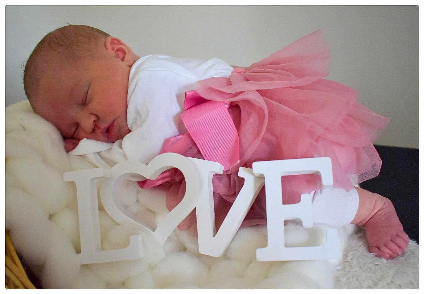 Iris participe au concours pour gagner de l'argent avec cette photo : baby, newborn, sleeping, pink_tutu, white_clothing, love_sign, blanket, soft_texture, cute, infant, peaceful, resting, indoors, portrait, closeup, tulle_skirt, decorative_letters, sleep, tiny_feet, cozy