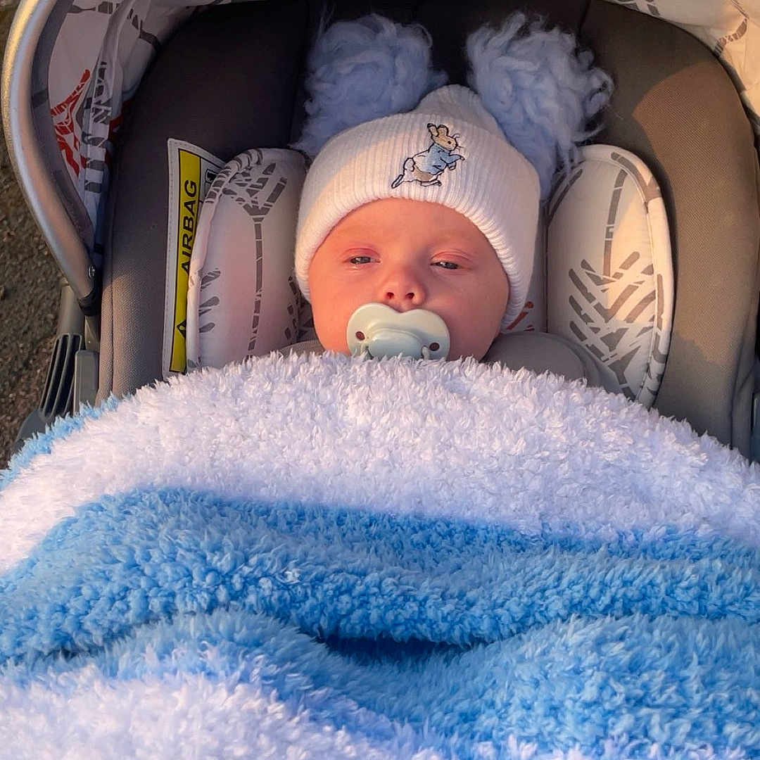 Kayden is registered to the contest to win money with this photo: baby, ball, bed, blanket, bonnet, cap, car, clothing, face, furniture, hat, head, newborn, person, photography, portrait, rugby, rugbyball, sleeping, sport