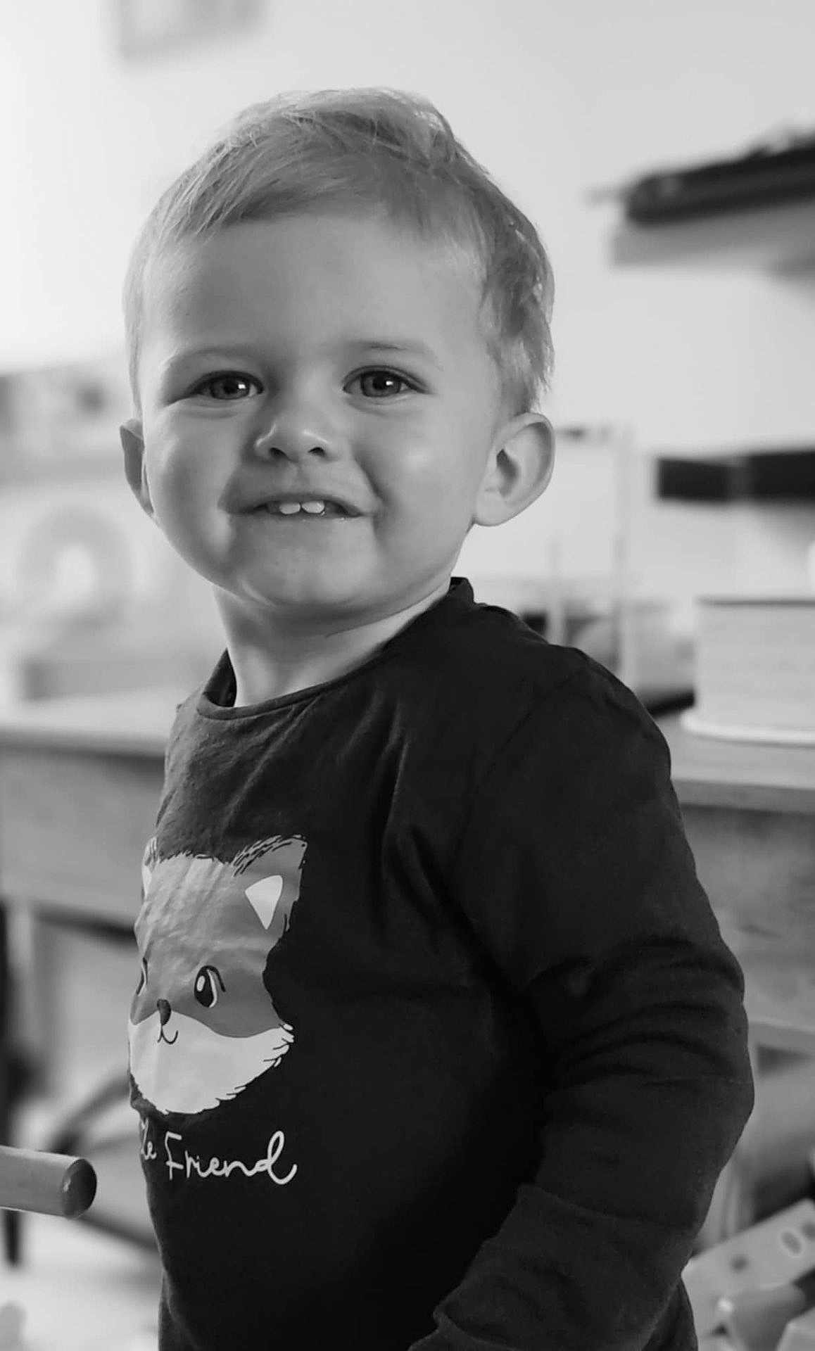 Augustus a rejoint le concours — aidez-le/la à gagner de superbes lots ! child, toddler, smiling, indoor, black_and_white, face, cute, clothing, fox_graphic, shirt, person, portrait, happy, young, hair, eyes, furniture, background, blurred, standing