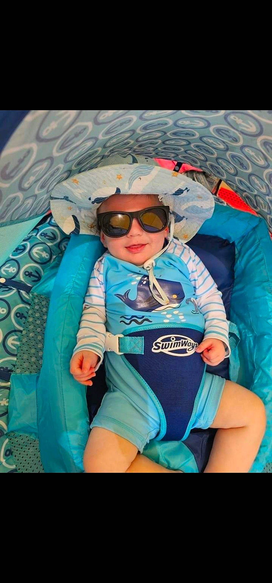 Declan is registered to the contest to win money with this photo: azure, baby, baby_toddler_clothing, child, electric_blue, eyewear, fashion_accessory, fun, glasses, goggles, headwear, pattern, person, personal_protective_equipment, pink, recreation, sitting, sleeve, sunglasses, thigh