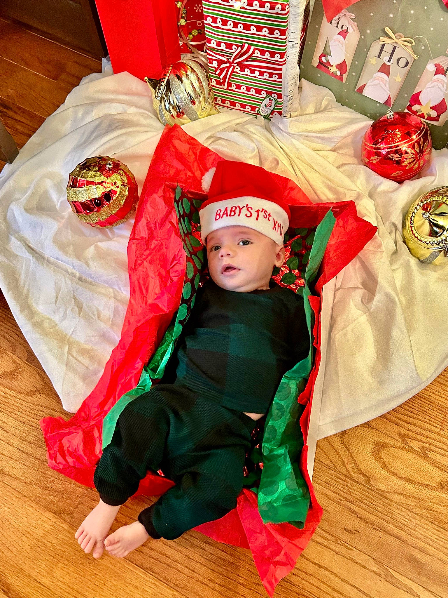 Brayden is registered to the contest to win money with this photo: baby, baby_toddler_clothing, carmine, child, christmas, christmas_decoration, christmas_eve, comfort, costume_hat, event, fictional_character, flooring, foot, happy, headwear, holiday, interior_design, linens, person, red