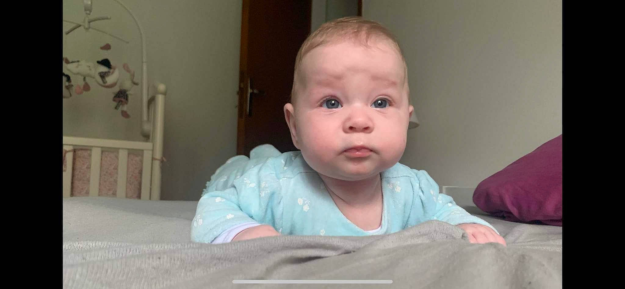 Rose participe au concours pour gagner de l'argent avec cette photo : arm, baby, baby_toddler_clothing, cheek, comfort, eye, eyebrow, gesture, hair, hand, head, iris, linens, mouth, neck, nose, person, skin, sleeve, smile