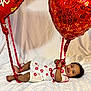 Santi is registered to the contest to win money with this photo: baby, infant, child, balloons, red_balloon, heart_balloon, ribbon, ribbons, kiss_prints, onesie, smile, happy, lying_down, white_sheet, curly_hair, portrait, studio_shot, celebration, cute, hands