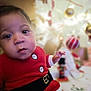 Aaron a rejoint le concours — aidez-le/la à gagner de superbes lots ! baby, blurred_background, child, christmas, closeup, cute, decorations, face, festive, hand, holiday, holiday_season, indoors, infant, person, portrait, red_clothing, santa_outfit, tree, warm_lighting