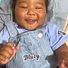 Asiyah is registered to the contest to win money with this photo: baby, child, smiling, overalls, blue_clothing, curly_hair, happy, portrait, infant, person, cute, sitting, indoor, blanket, fabric, button, hand, face, skin, toddler