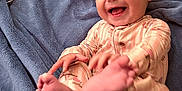 Jovie is registered to the contest to win money with this photo: baby, infant, smiling, pajamas, feet, blanket, pacifier, playful, happy, child, cute, indoors, soft, pastel_colors, lying_down, closeup, face, hand, skin, cozy